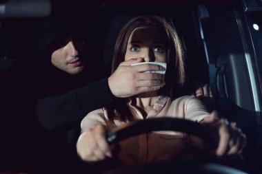 thief attacking beautiful frightened woman in car at night clipart