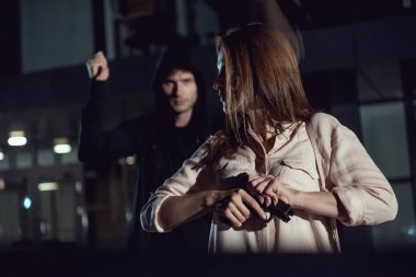 woman holding gun near thief at night clipart