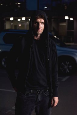 gece otoparkta kamera bakarak siyah hoodie hırsız