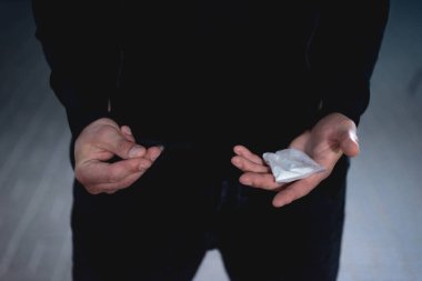 cropped view of thief holding drugs in plastic zipper bag clipart