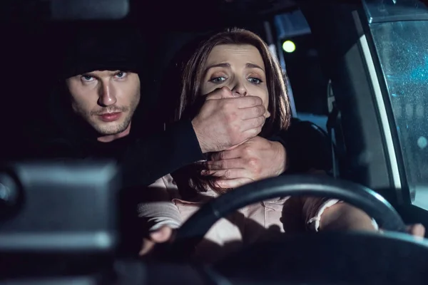 夜間に車の中で怖い女性の口を覆う泥棒 — ストック写真
