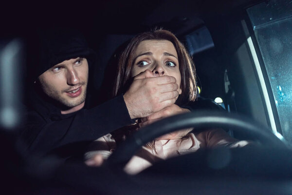 Вор душит красивую испуганную женщину в машине
