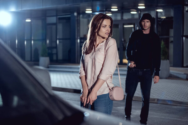 woman with gun near thief at night in parking lot