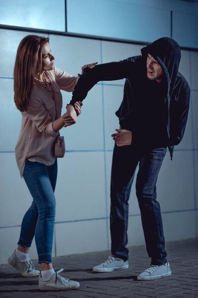 attractive woman fighting with thief in underpass