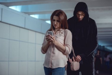 hırsız alt geçit akıllı telefon kullanarak kadın çanta para çalmak