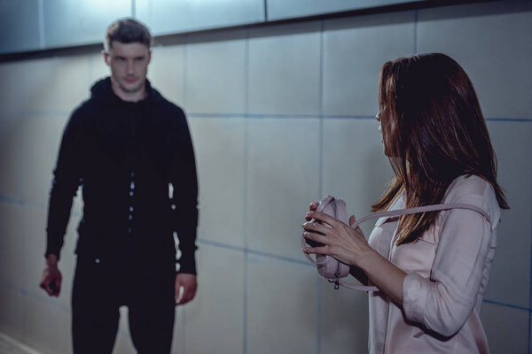 Женщина держит сумку и смотрит на вора в подземке
