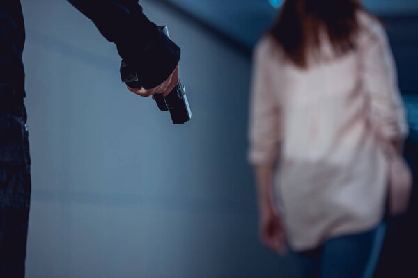 селективный фокус грабителя, держащего пистолет рядом с женщиной
