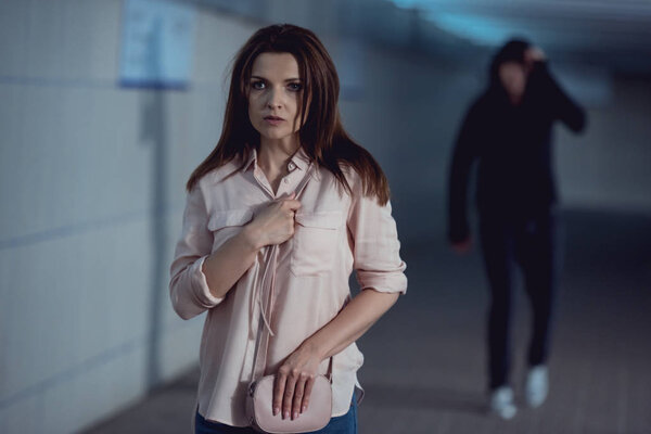 frightened woman running away from thief in underpass