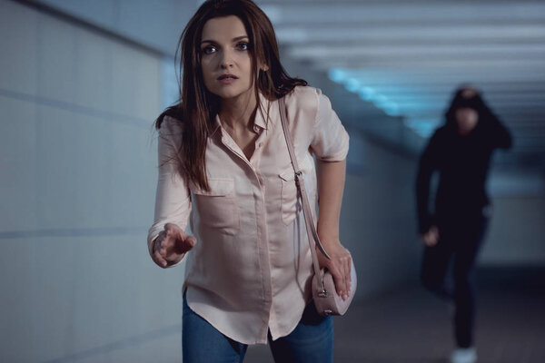 beautiful woman running from thief in underpass