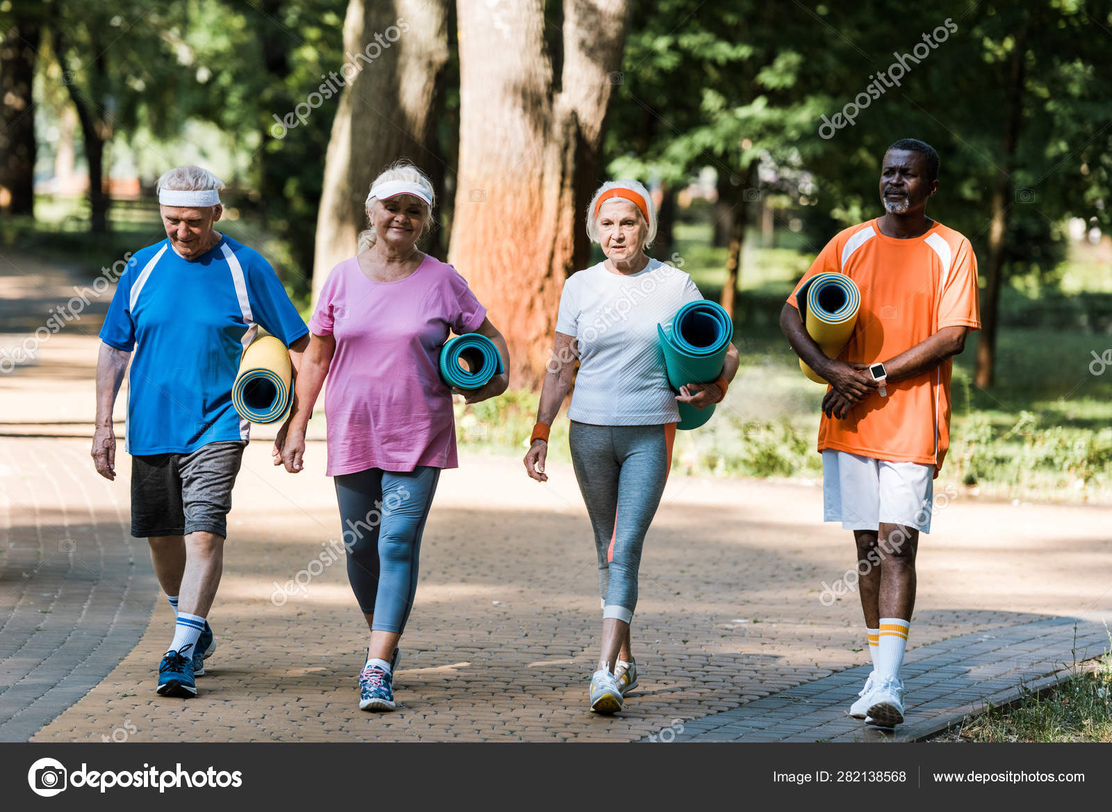 Happy Senior Multicultural Pensioners Holding Fitness Mats Walking