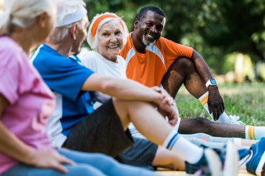 fitness paspaslar üzerinde oturan spor mutlu çok kültürlü erkek ve kadınların seçici odak 