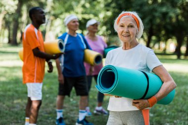çok kültürlü emekliler yakın gülümseyen fitness mat ile mutlu emekli kadının seçici odak 