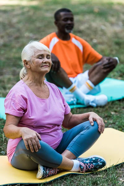 Selektiv Fokusering Pensionerad Kvinna Med Slutna Ögon Sitter Med Korsade — Stockfoto