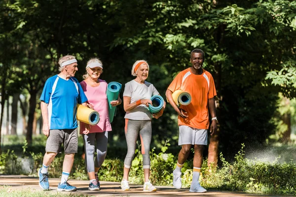 Pensionati Positivi Multiculturali Che Tengono Tappeti Fitness Camminano Nel Parco — Foto Stock