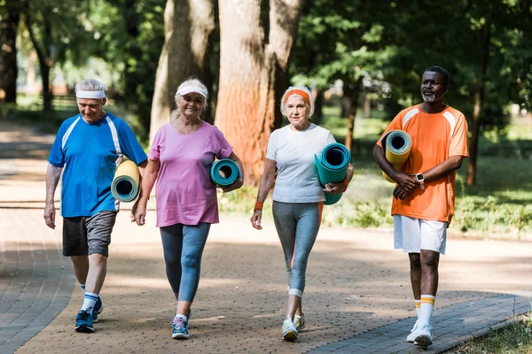 Reformados Seniores Multiculturais Felizes Segurando Tapetes Fitness Andando Passarela Parque — Fotografia de Stock