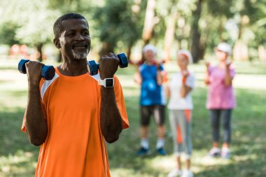 parkta dumbbells tutan üst düzey afro-Amerikan adam seçici odak 