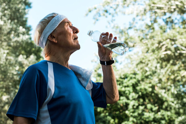 Низкий угол обзора пенсионера, держащего бутылку с водой
 