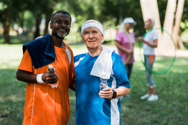 селективный фокус спортивных мультикультурных пенсионеров, держащих бутылки с водой
 