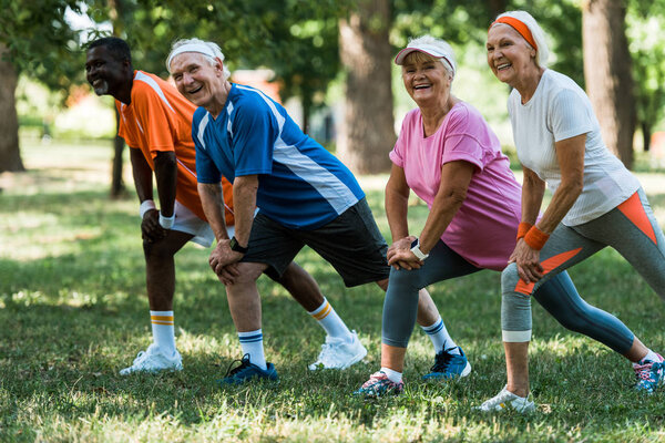 happy senior and multicultural people exercising on grass 