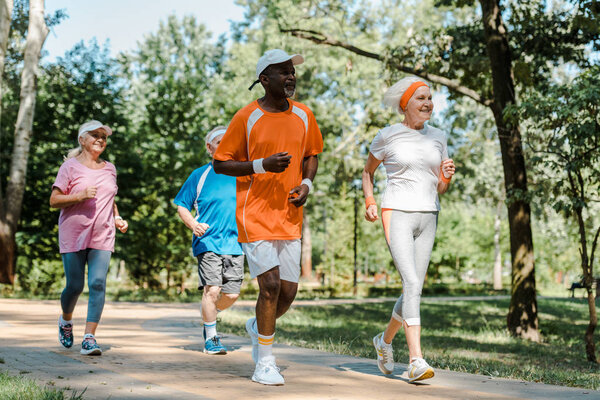 happy multicultural and retired men and women running in park 