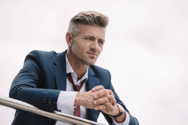 takım elbiseli yakışıklı işadamı sıkıştırılmış elleri ile dışarıda ayakta