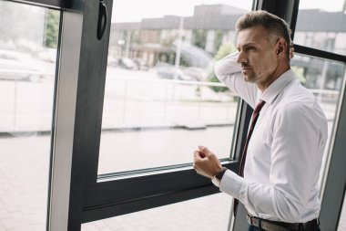 pencere yakınında duran takım elbiseli işadamı memnun değil 