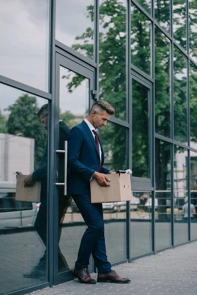 建物の近くに立ってカートンボックスを見て動揺し 解雇されたビジネスマン — ストック写真