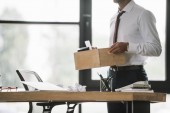 cropped view of dismissed businessman holding wooden box in modern office 