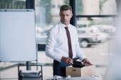 selective focus of fired businessman standing near table with wooden box 