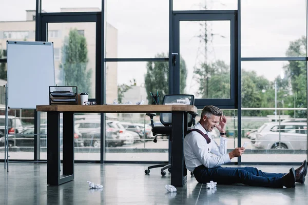 Homem Negócios Estressado Sentado Chão Perto Mesa Escritório Moderno — Fotografia de Stock