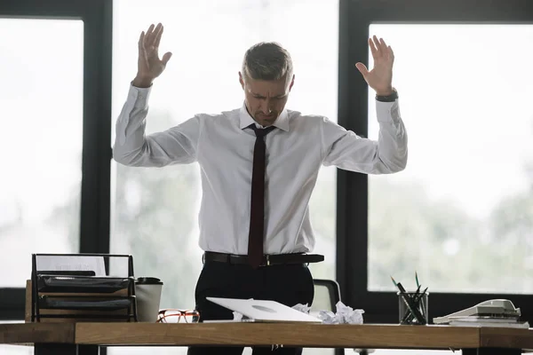 Bonito Empresário Gestos Enquanto Olhando Para Mesa Escritório — Fotografia de Stock