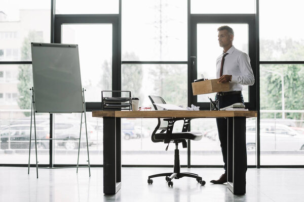 dismissed businessman holding wooden box in modern office 