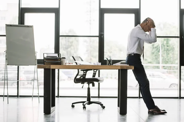 Pengusaha Tampan Menyentuh Kepala Sambil Berdiri Dekat Meja Kantor Modern — Stok Foto