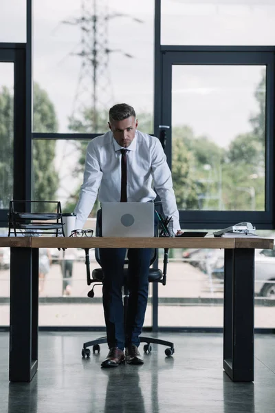 Бизнесмен Стоящий Возле Стола Ноутбука Смотрящий Камеру Офисе — стоковое фото