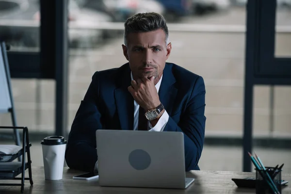 Guapo Hombre Negocios Mirando Cámara Mientras Toca Cara Cerca Computadora — Foto de Stock