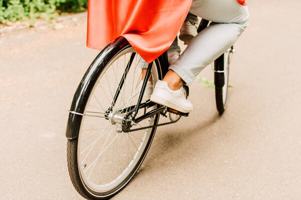 cropped view of dad with son in red cloak riding bicycle