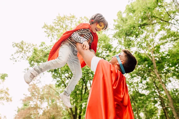 Padre Costume Supereroe Che Tiene Figlio Mano Mentre Bambino Ride — Foto Stock