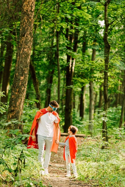 Ganzkörperansicht Von Vater Und Sohn Die Superheldenkostümen Wald Stehen Und — Stockfoto
