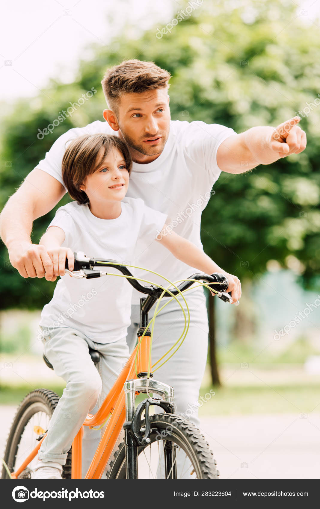 Father Son Looking Forward While Kid Riding Bicycle Dad Pointing Stock