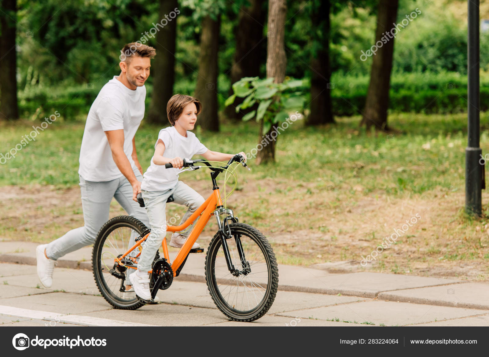 Full Length View Father Pushing Sit Bike Running Son While Stock Photo AndrewLozovyi 283224064