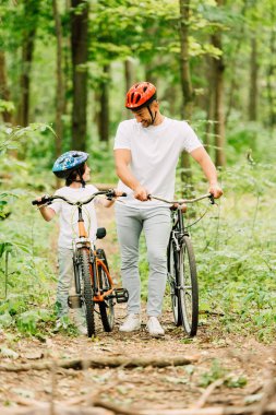 ormanda bisikletle yürüyen baba ve oğulun tam boy görünümü