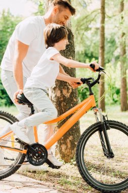 çocuğun bisiklete bindiği ve babanın çocuğun yanında yürümesi ve bisikletin oturması 