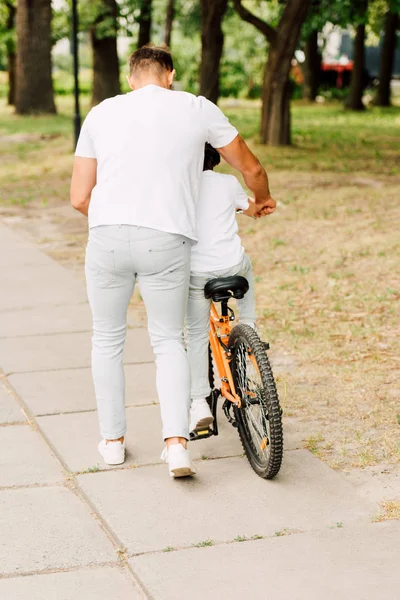 Pełny Widok Długości Syna Jazdy Rowerem Podczas Gdy Ojciec Pomaga — Zdjęcie stockowe