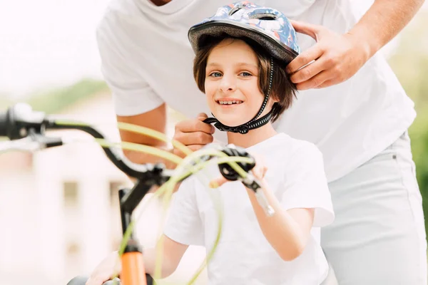 Selektive Fokussierung Glücklicher Sohn Blickt Kamera Während Vater Helm Aufsetzt — Stockfoto