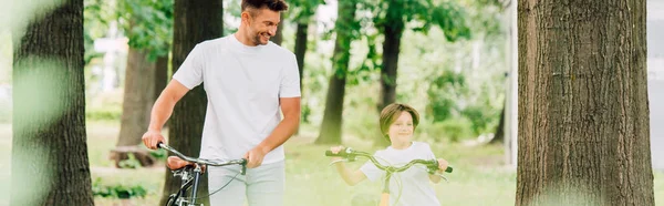 Plano Panorámico Padre Hijo Caminando Bosque Con Bicicletas Sonriendo Mientras —  Fotos de Stock