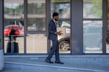 karton kutu taşıyan takım elbiseli afrikalı-Amerikalı işadamı görevden 