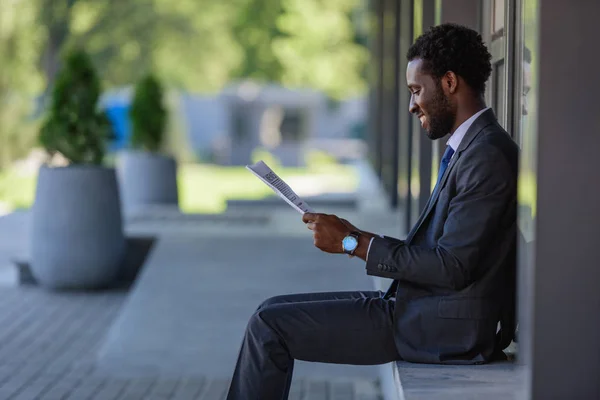 Smiling African American Businessman Sitting Parapet Reading Newspaper — Stock Photo, Image