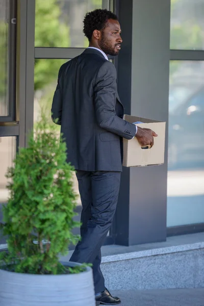 Ευγενικός Αφρικανός Αμερικανός Επιχειρηματίας Κοιτάζοντας Μακριά Ενώ Μεταφέρουν Χαρτοκιβώτιο — Φωτογραφία Αρχείου