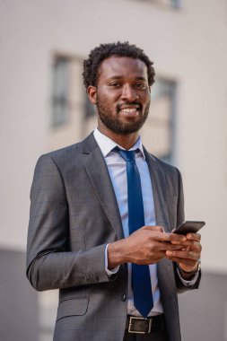 yakışıklı afro-amerikan adam akıllı telefon kullanarak ve kamera gülümseyerek