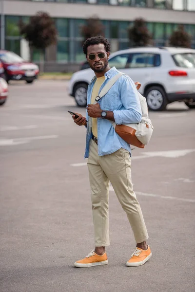 Guapo Afroamericano Hombre Gafas Sol Sosteniendo Teléfono Inteligente Mientras Está — Foto de Stock